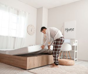 A man setting up a mattress.